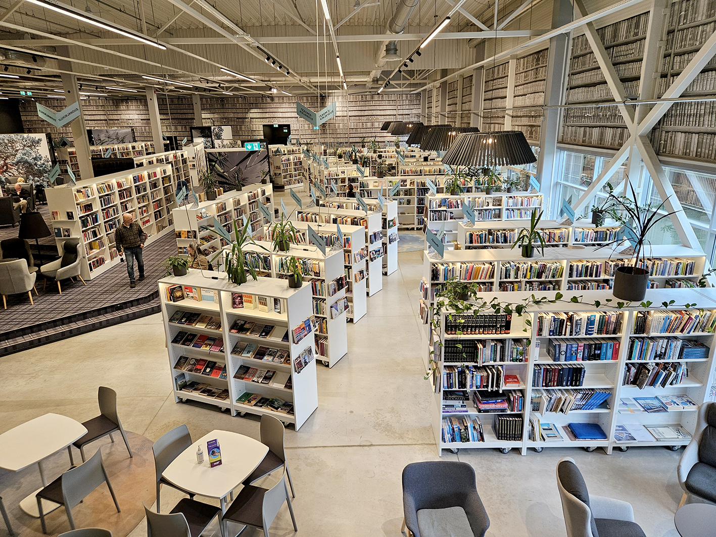 Das Bild zeigt die Inneneinrichtung der Stadtbibliothek Viimsi. Man sieht eine Reihe von weißen Regalen mit Büchern und die Decken- und Wändekonstruktion aus Metallstreben. 